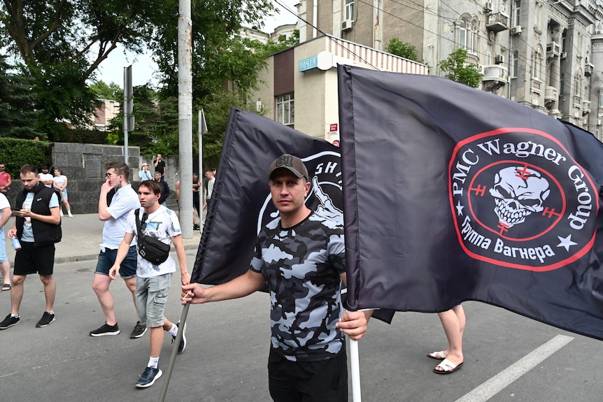 A supporter of Wagner private mercenary group holds flags near the headquarters of the Southern Military District.