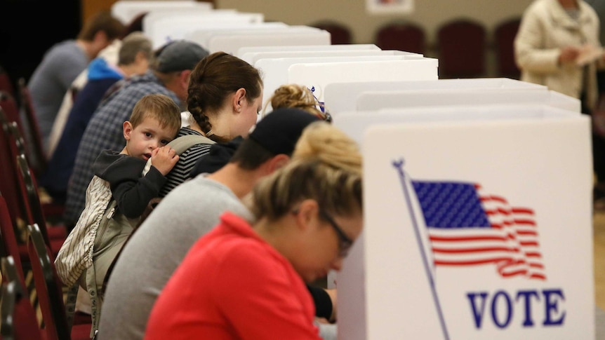 A baby hangs out as people vote in a Baptist Church