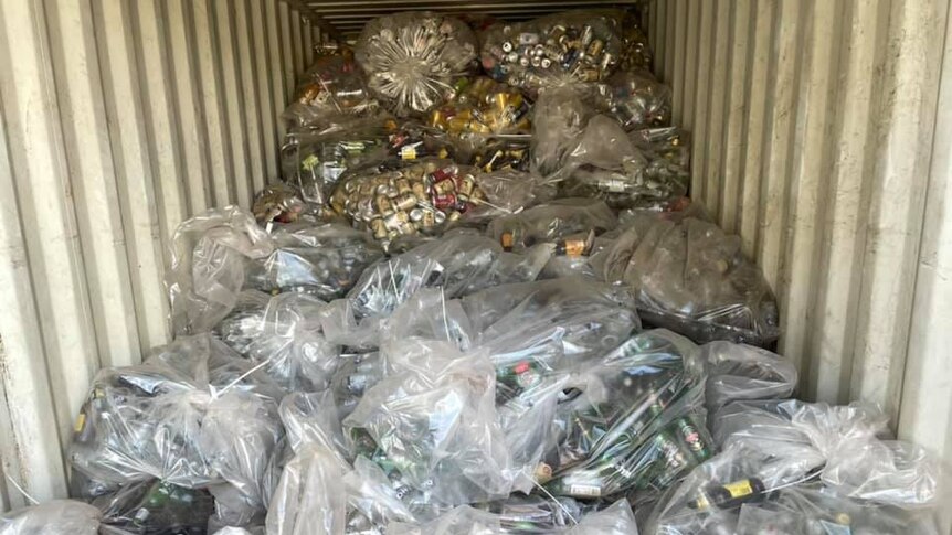 A shipping container loaded up with plastic bags full of old bottles and cans