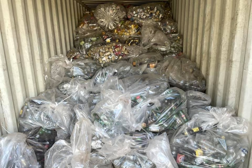 A shipping container loaded up with plastic bags full of old bottles and cans
