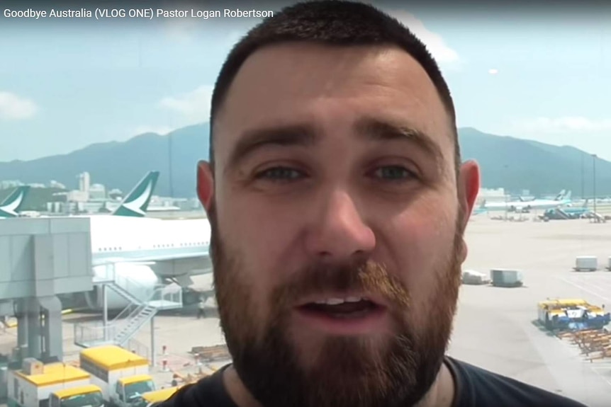 Logan Robertson speaking at an airport in New Zealand, planes visible in the background