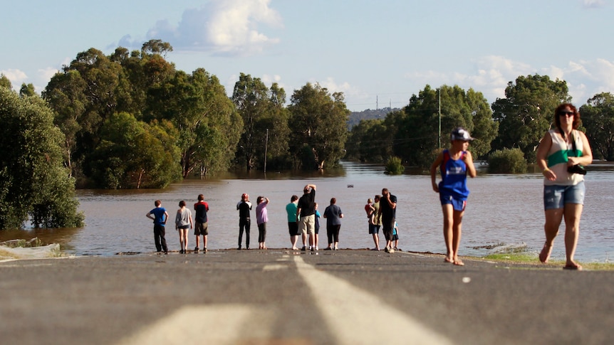 Local residents look at a road submerged in flood waters near Wagga Wagga