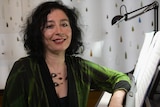 Composer Elena Kats-Chernin sitting at piano with green shirt on.