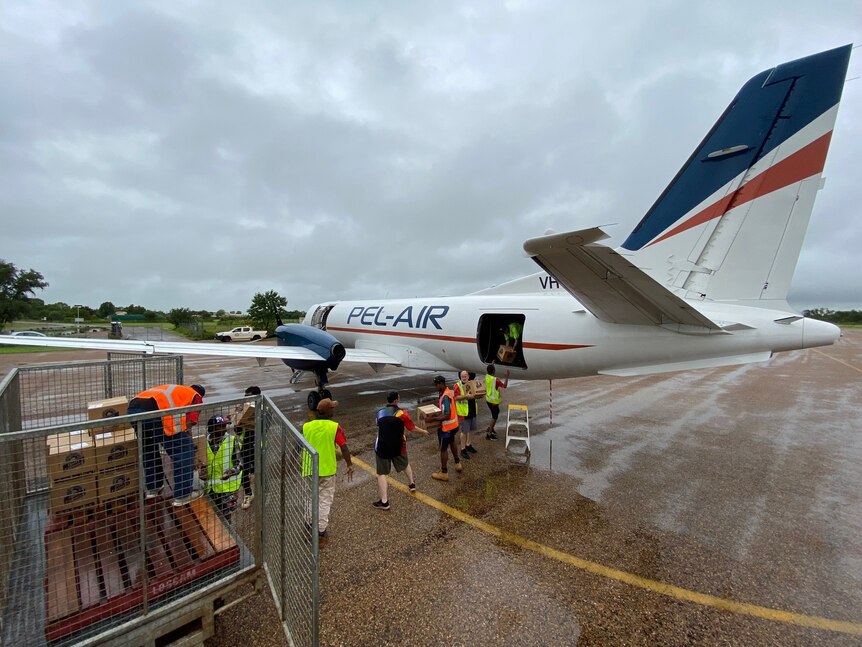 Workers unload a plane on a tarmac
