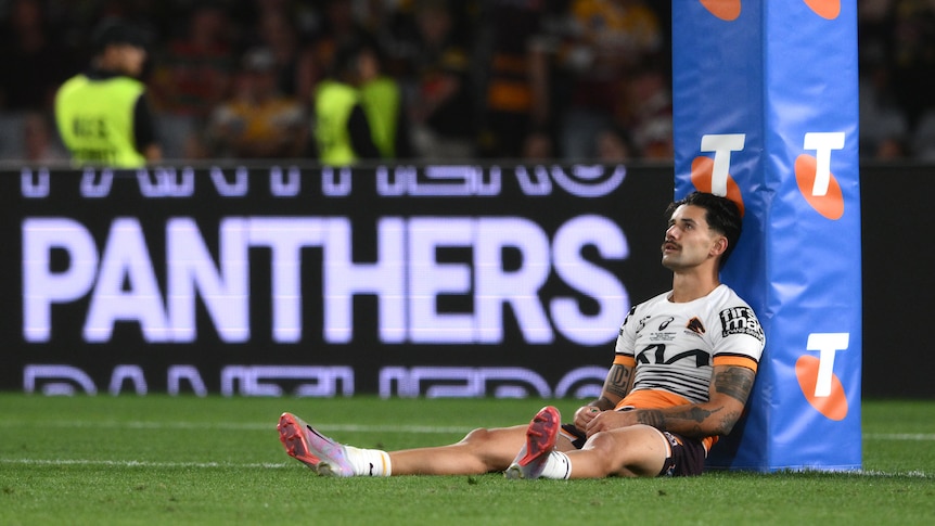 Jesse Arthars of the Brisbane Broncos sits against a goalpost after the NRL grand final.