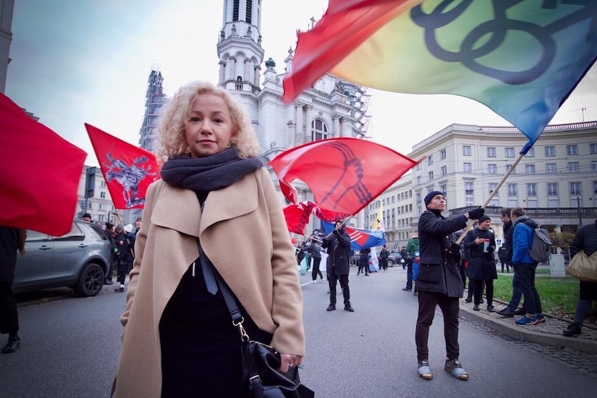 A woman in a coat standing among protesters waving flags