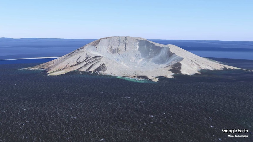 Whakaari rises out of the sea its crater clearly visible.