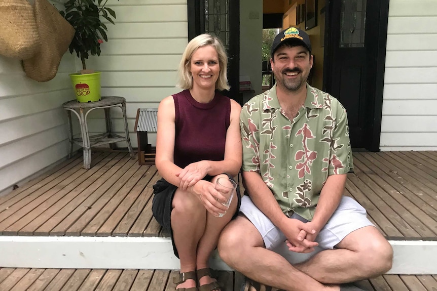 a smiling man and woman sitting on the steps of a house