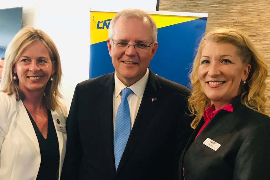 two blonde women stand with former prime mininster scott morrison. they are angie bell and fran ward.