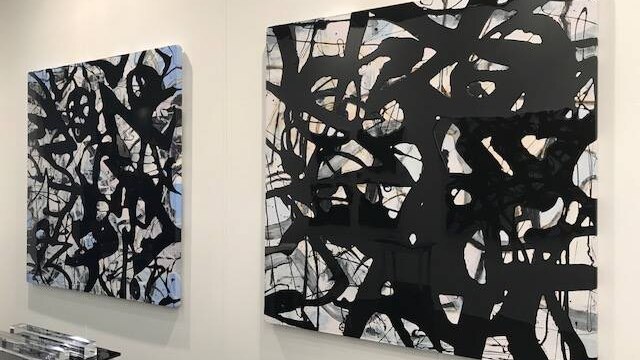 Two large paintings hang on a wall.