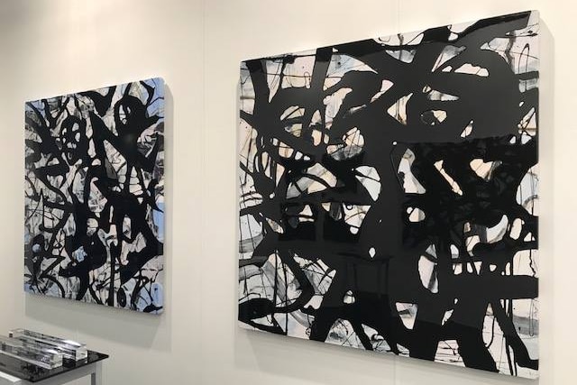Two large paintings hang on a wall.