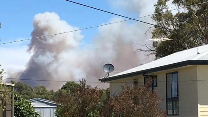 Smoke rises behind a house.