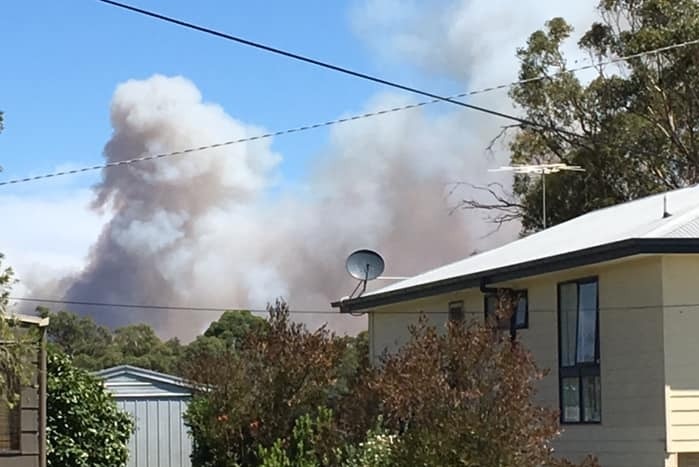 Smoke rises behind a house.