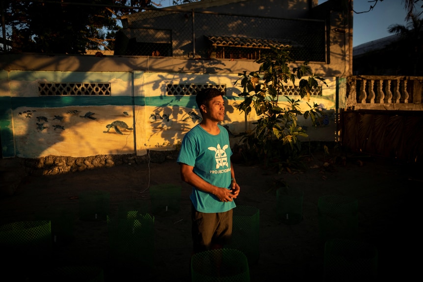 A man stands in front of a building and looks into the distance. 