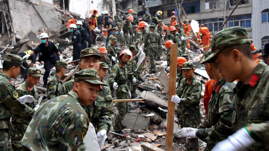 Rescuers clear the debris to search for victims on the site of collapsed residential buildings in Wenzhou city, 10 October 2016.