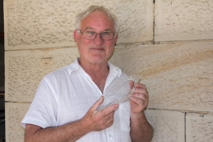 A man holding a handmade sculptured glass dish