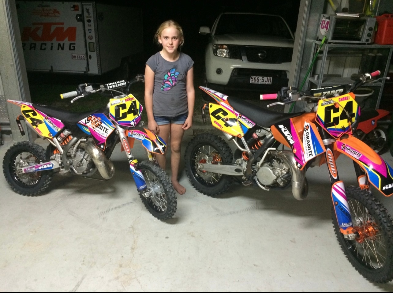 Uma jovem parada entre duas motos.