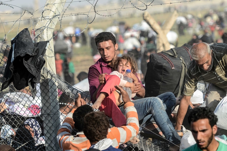 A man carries a girl as Syrians flee to Turkey