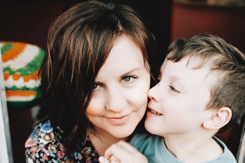 A  mother smiling as her seven year old son looks at  her.