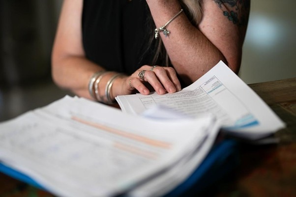 Una mujer revisa documentos mientras habla por teléfono. 