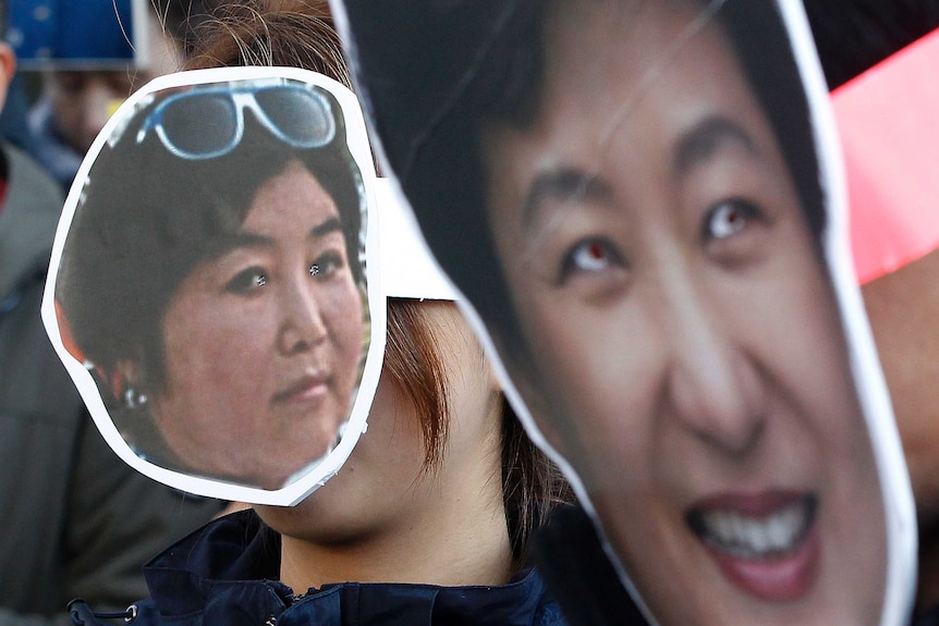 South Korean protesters wear cardboard masks of President Park Geun-hye and her friend Choi Soon-sil