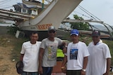 Filipino fishermen stand in front of their fishing boat.