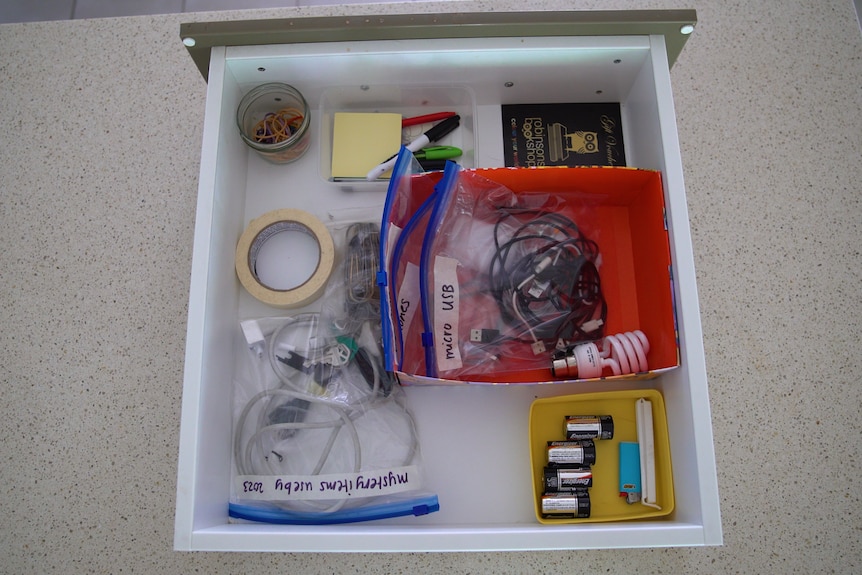 A photo of an organised drawer with container and small gift boxes with zip lock bags featuring miscellaneous items.
