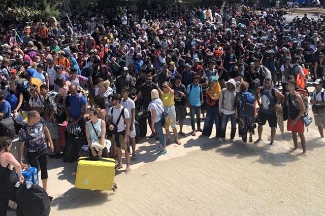 Crowds wait on a beach