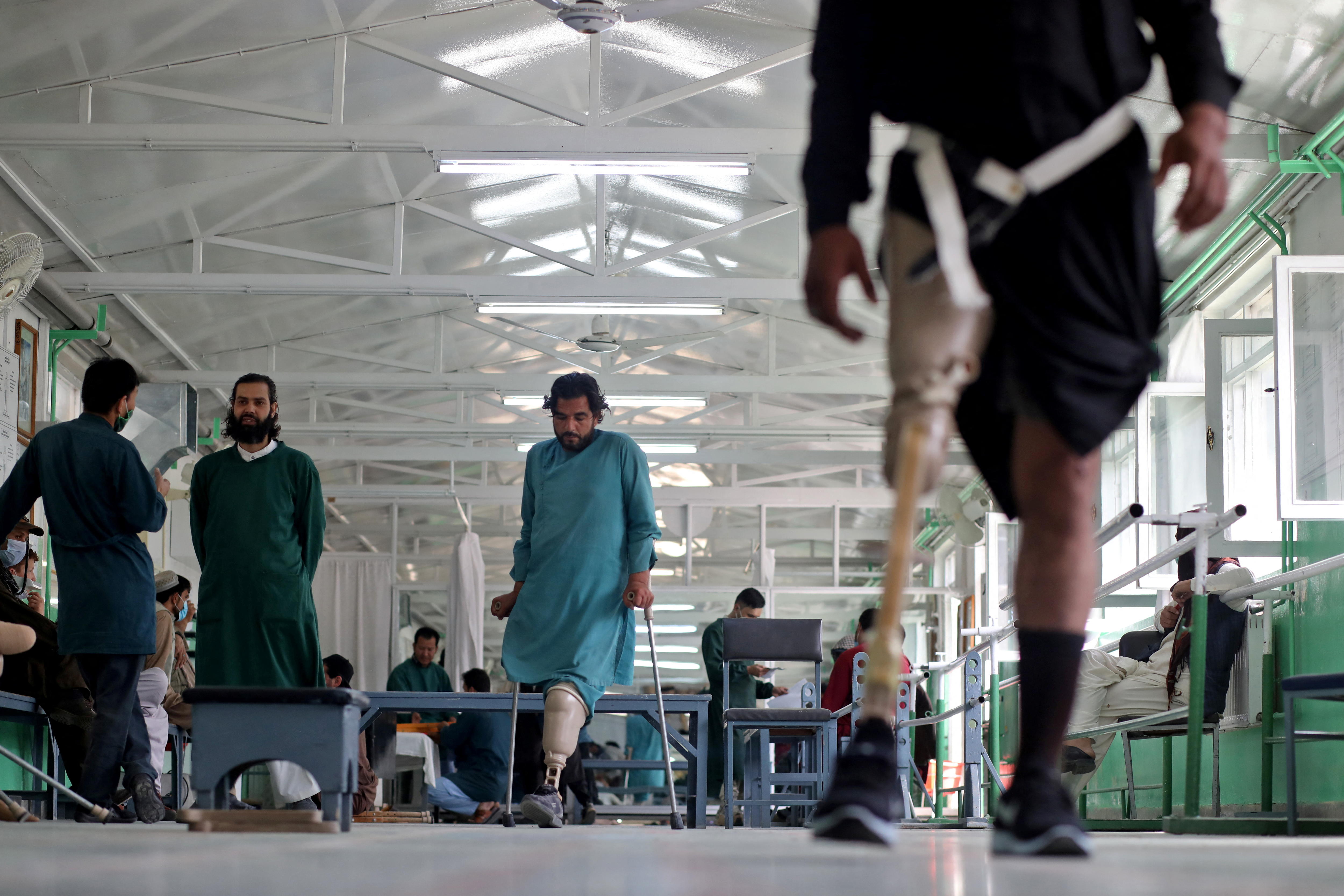 Man in foreground  with a prosethic leg in a hospital 