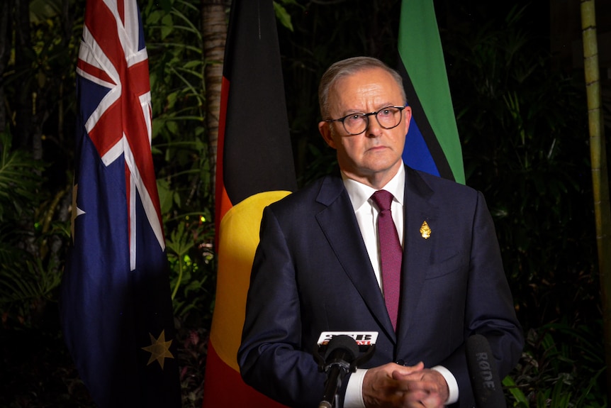 Anthony Albanese in front of Australian, Aboriginal and Torres Strait Islander flags
