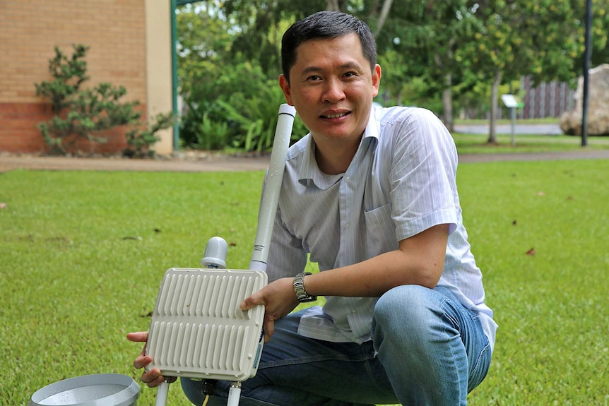 Professor Wei Xiang holds an Internet-of-Things-enabled rain gauge