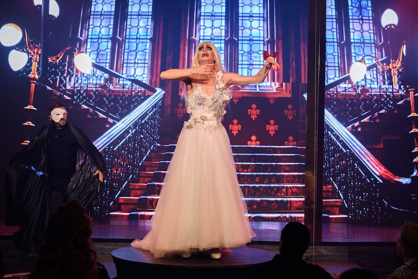 A drag queen performing in a white dress.