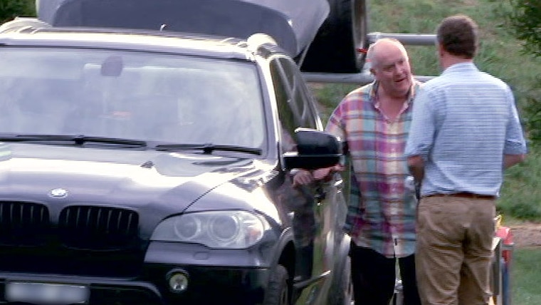 Stephen O'Neill talks to Dan Oakes beside a car.
