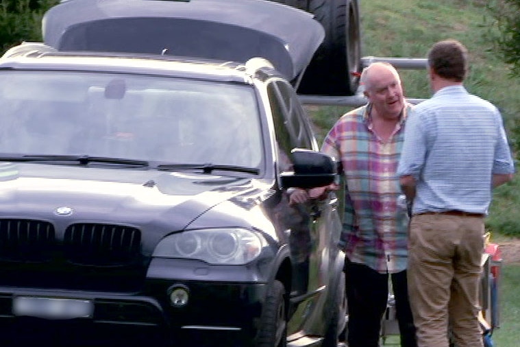 Stephen O'Neill talks to Dan Oakes beside a car.