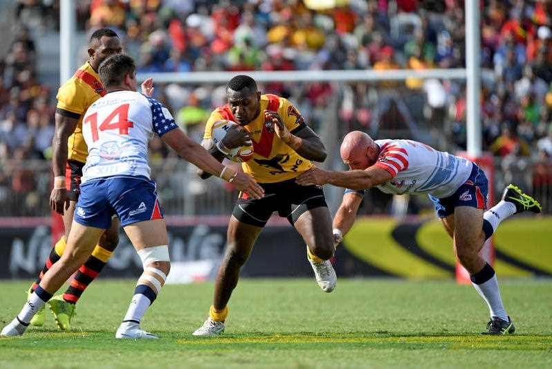 Kato Ottio of Papua New Guinea is seen from front-on being tackled by two players.