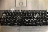 A black and white photo of about 60 young apprentices in a gymnasium.