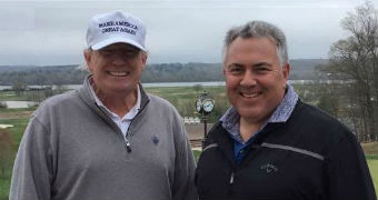 Donald Trump, wearing a white cap and sloppy joe, and Joe Hockey, also in a sloppy joe, stand next to each other grinning