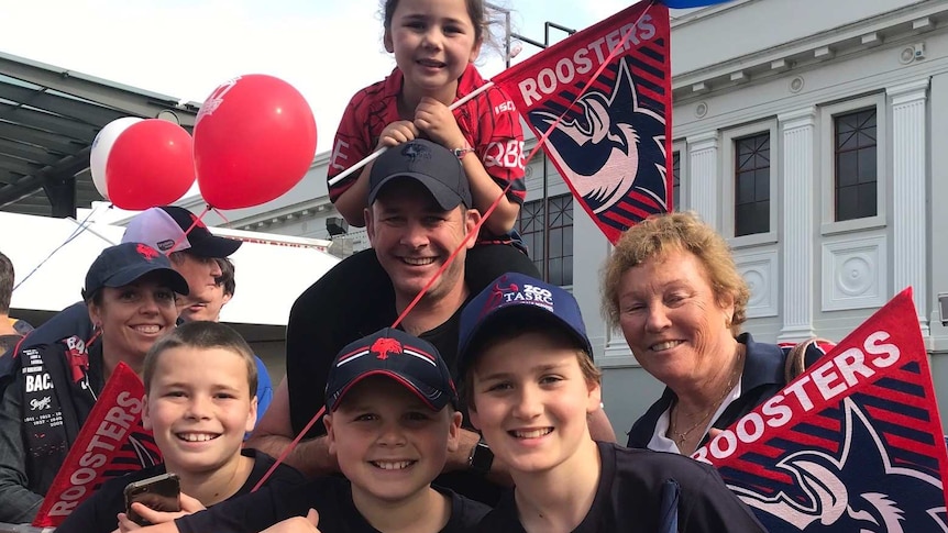 A group of people waving Roosters flags.