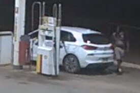 Blurry shot of white car seen refueling in a midwest town