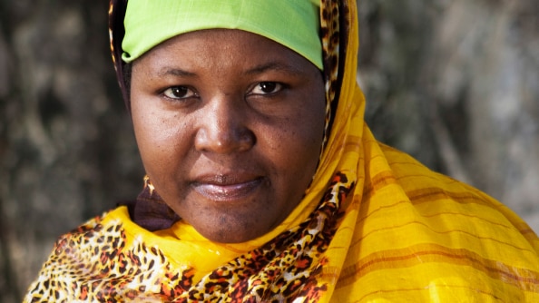 Portrait of Somalian refugee Mariam wearing a green headscarf and yellow head covering