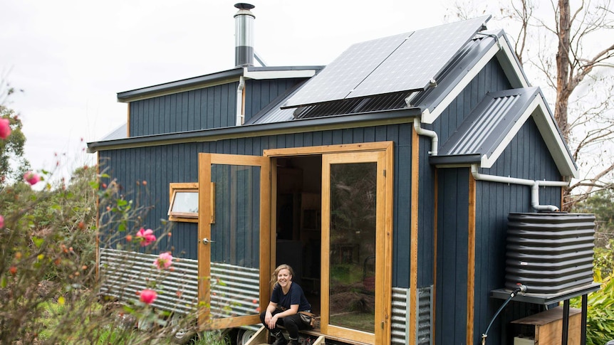 Sarah Smethurst sits on the stairs ouside her tiny house.
