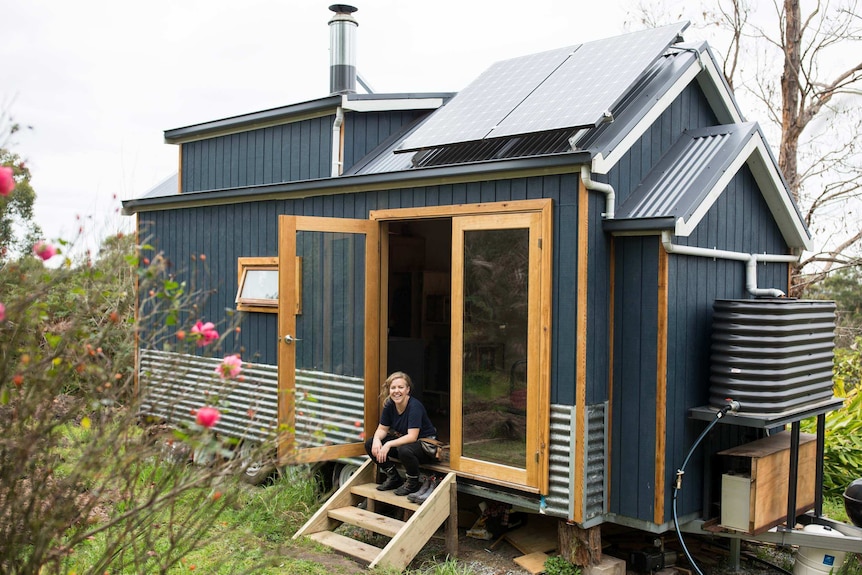 Sarah Smethurst sits on the stairs ouside her tiny house.