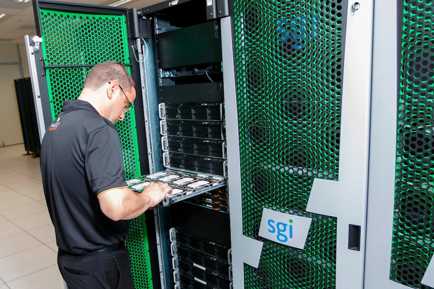 Man standing fixing the supercomputer racks and internal system 