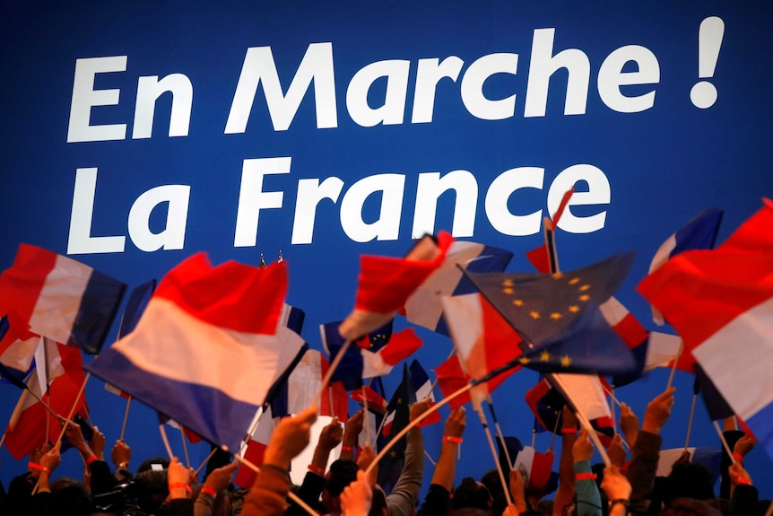Supporters of Emmanuel Macron wave French flags.