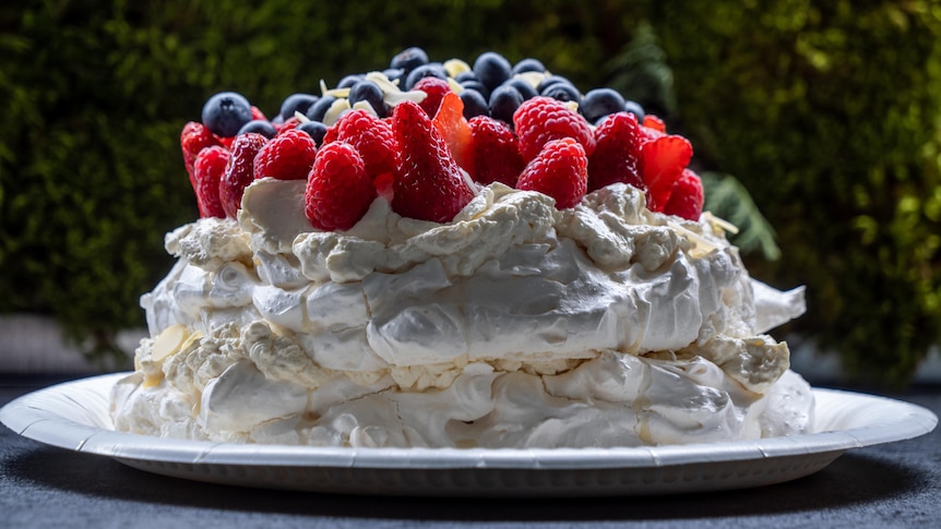 A pavlova topped with assorted fruit