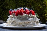 A pavlova topped with assorted fruit