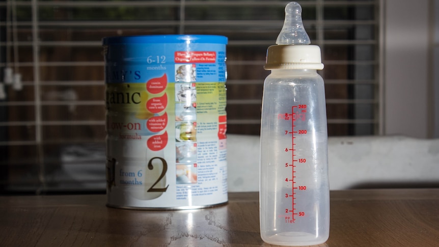 A bottle and can of baby formula sit on a table.