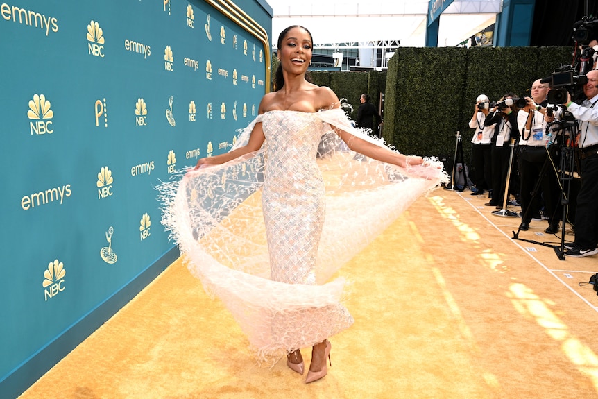Zuri Hall wears a white, shimmery beaded dress with a sheer spangled cape