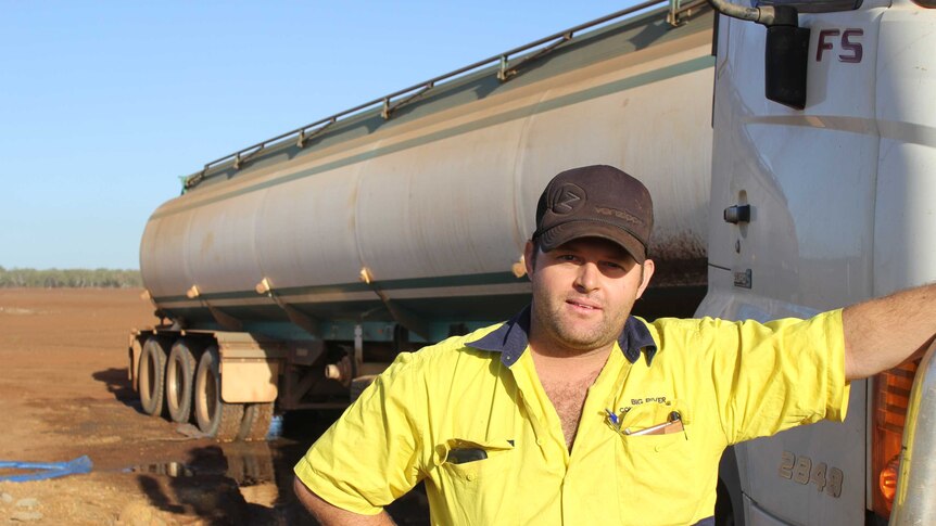 a man standing next to a water tanker