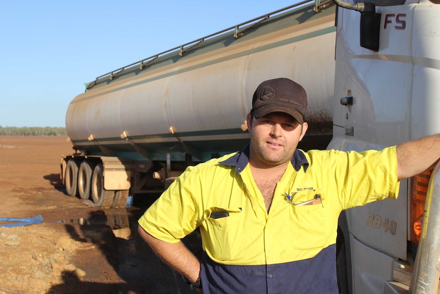 a man standing next to a water tanker